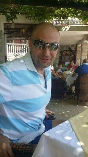 A smiling man with a light blue striped shirt sitting at a table with a red checkered tablecloth. Used as a residential review for professional loft insulation extraction in the Bradford and Shipley area.