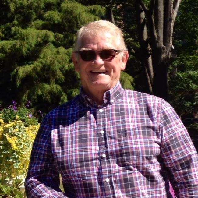A happy senior male customer in a checkered shirt and sunglasses, standing outdoors in a garden setting in Buckinghamshire after a successful loft insulation project with Spray Foam Removal UK.