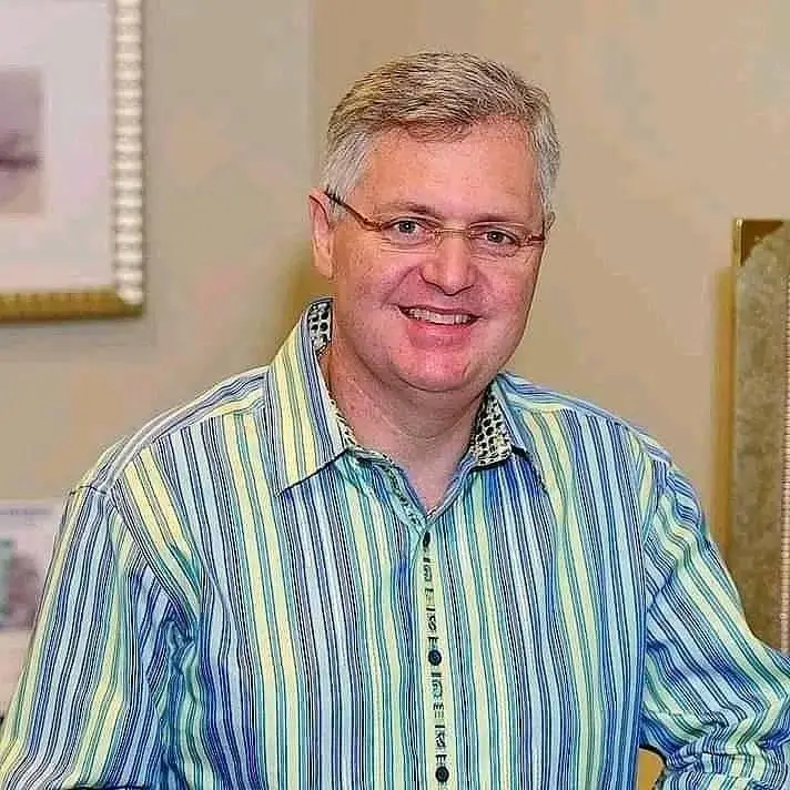 A smiling senior man with grey hair and glasses, wearing a bright green and blue striped shirt. This image represents a satisfied rural property owner in Chorley, Lancashire, who had spray foam professionally removed.