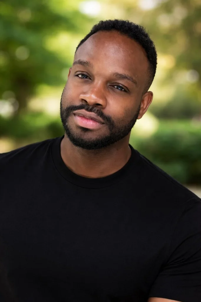 A close-up portrait of a Black man with short dark hair and a beard, wearing a black t-shirt, used as a customer testimonial for loft insulation removal services in Filton, Bristol.