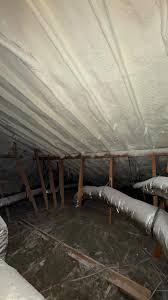 White breathable roof membrane and insulated pipes in loft space with exposed wooden rafters in West Yorkshire
