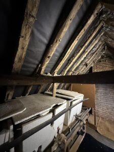 Black breathable roof membrane installed between exposed wooden rafters in a Wiltshire loft renovation