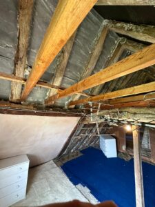 Exposed wooden roof rafters and breathable membrane with blue protective flooring in Oxfordshire loft conversion