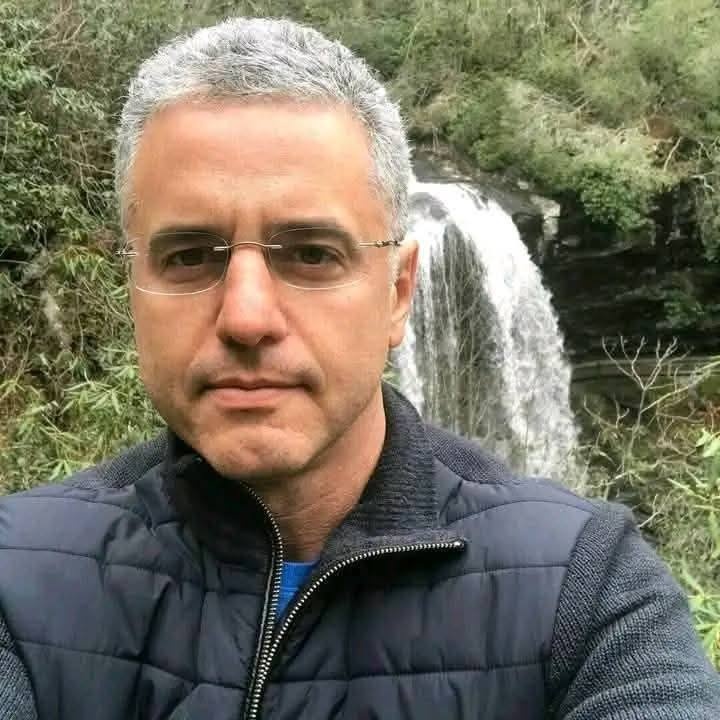 A portrait of a local male customer with glasses and grey hair, standing outdoors near a waterfall in Nottinghamshire, sharing his positive feedback after a spray foam removal job.