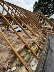 Exposed wooden roof rafters and loose mineral wool insulation during a loft renovation project in Staffordshire