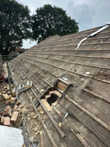 Roof stripped to battens with chimney removal site and debris during renovation in Shropshire