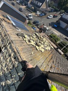 Roofer's POV during roof stripping with debris piles and solar panels visible in East Riding of Yorkshire
