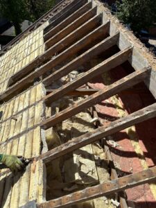 Exposed wooden roof rafters and old insulation during roof stripping renovation in Herefordshire