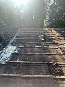 Exposed wooden roof battens and old membrane during roof stripping renovation in Leicestershire