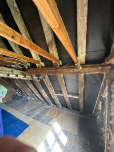 Black breathable roof membrane installed between wooden rafters during loft renovation in Berkshire