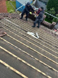 Two roofers installing wooden battens over a breathable membrane on a residential roof in Northamptonshire