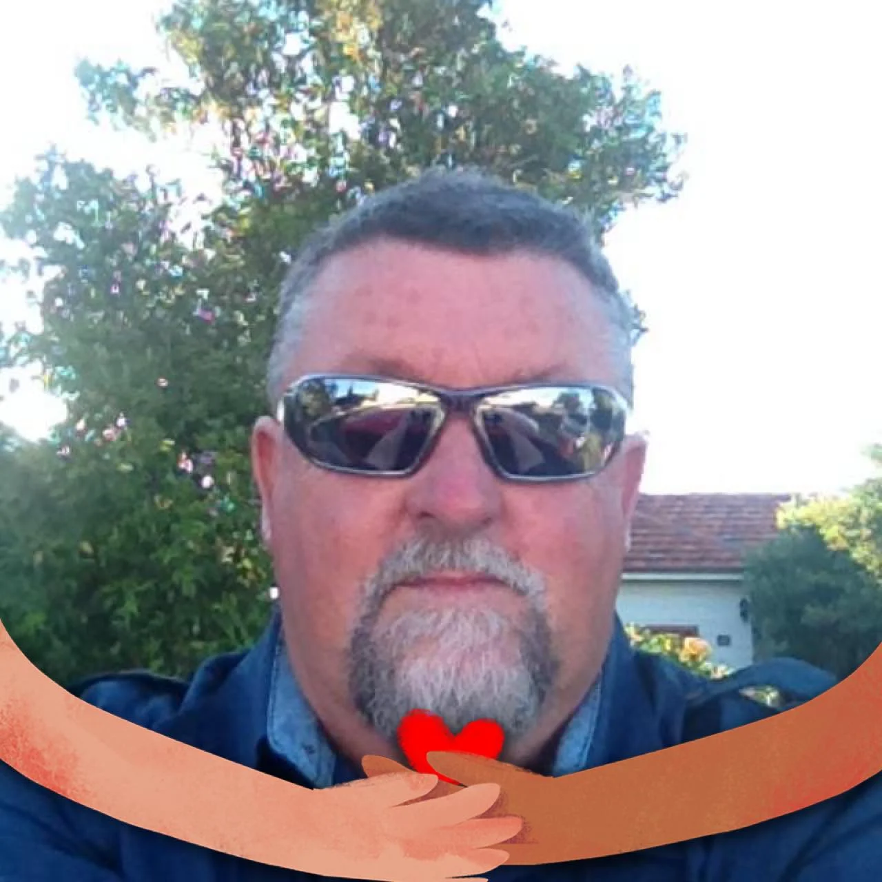 A portrait of a senior man with a grey goatee and sunglasses, wearing a blue shirt. He is outdoors with a residential house and trees in the background, used as a customer testimonial for roof insulation removal in Shrewsbury.