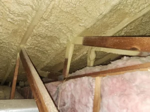 Spray foam insulation applied to roof rafters with fiberglass insulation between joists in London loft