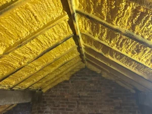 Yellow spray foam insulation fully applied to wooden roof rafters and ceiling in a Hertfordshire loft