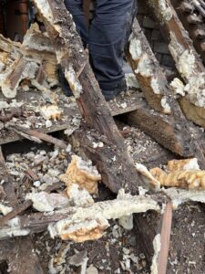 Close-up of decaying wooden roof beams and debris being removed during renovation in West Sussex