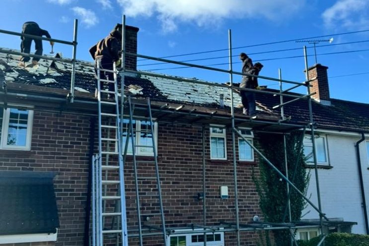 Professional roofing contractors working on terraced house roof in Bedfordshire with scaffolding for roof repair and tile replacement