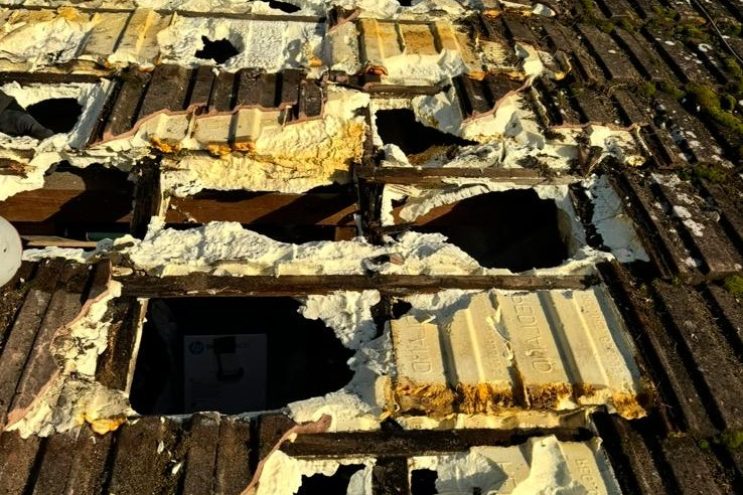 Spray foam insulation removal in Greater London, showing deteriorated roof tiles and exposed timber rafters during foam extraction, professional roof restoration service