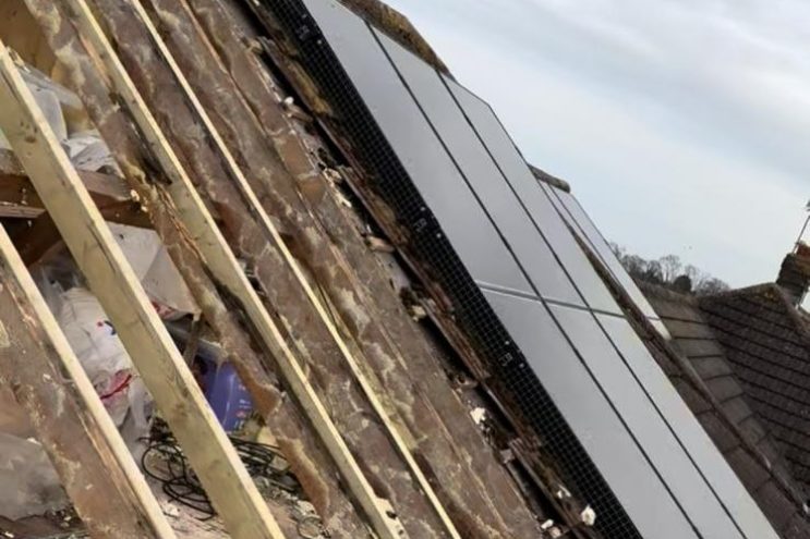 Spray foam insulation removal in Merseyside, showing roof repair work around solar panels and exposed timber rafters