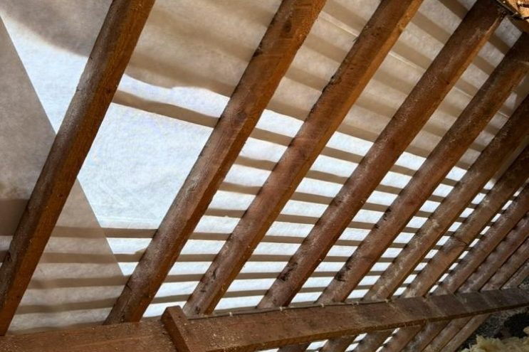 Spray foam insulation removal in Surrey showing timber roof rafters and loft insulation, professional extraction and roof restoration service