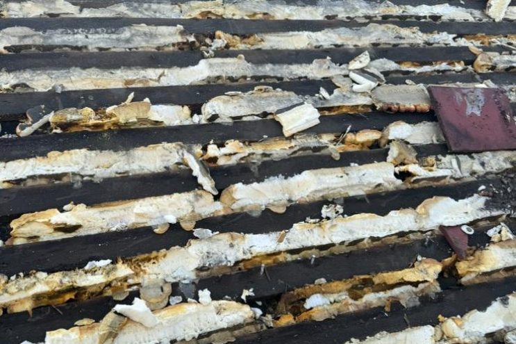 Spray foam insulation removal in West Sussex showing exposed timber battens and foam residue, professional roof restoration service